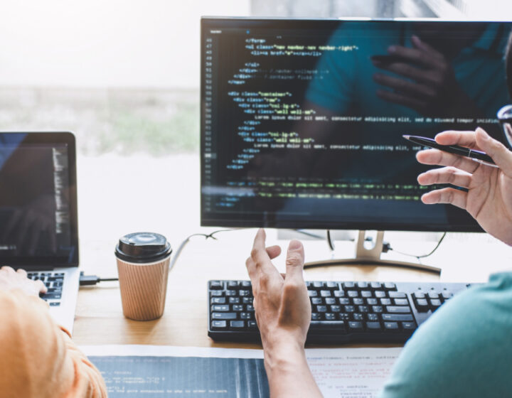 Twee developers kijken naar beeldscherm met code