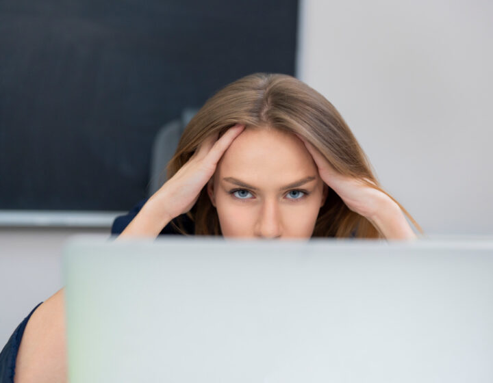 Jonge vrouw kijkt bedenkelijk naar haar beeldscherm